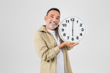 Smiling man holding a large clock on white background