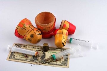 A Russian nesting doll, a dollar, a syringe and a thimble in a still life. - obrazy, fototapety, plakaty