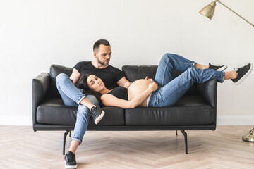 Pregnant woman with husband laying on couch