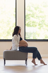 Pregnant woman sitting on bench in room