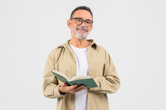 Man reading a green book attentively on white background