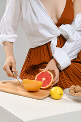 A woman cut a juicy grapefruit in half