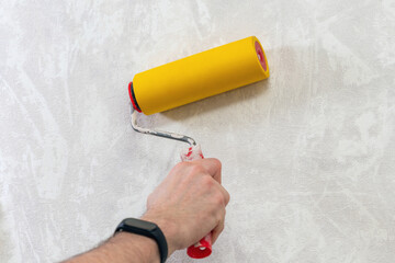 A man's hand with a roller for smoothing wallpaper. Wallpapering the apartment