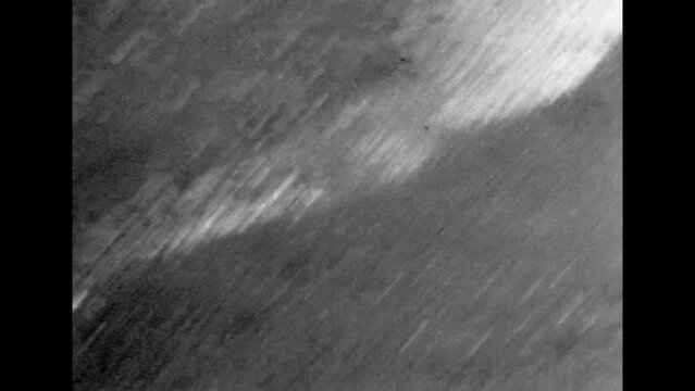 Close up, sea foam waves on sandy beach on black white film. Old footage of foamy landscape. White foam on black volcanic sand. Abstract ocean nature. Monochrome coast. Retro vintage archive 1980s