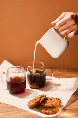 Woman pouring milk into coffee cups in the morning