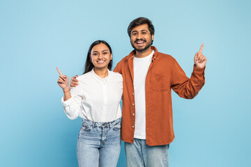 Couple pointing upwards together on blue background