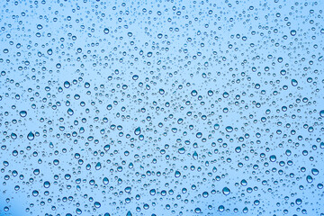 Raindrops on Window. Water drop texture on blue background. Close up water drop texture on blue...