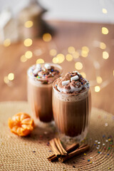 Two glass cups with hot chocolate stand on a wooden table