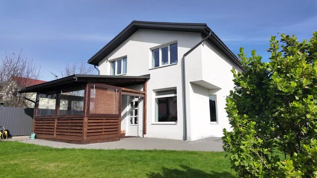 Real modern European house exterior and backyard in spring time. Private backyard architecture. Patio area and lawn