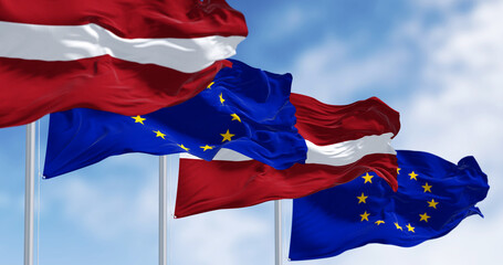 Flags of Latvia and the European Union waving on a clear day - obrazy, fototapety, plakaty