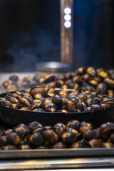 Close-up of roasted chestnuts outside in the evening, Istanbul, Turkey. Street food. Vertical photo
