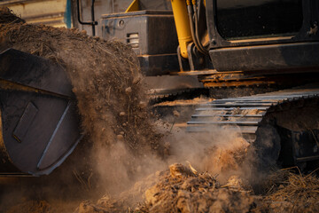 Selective focus on metal bucket teeth of backhoe digging soil. Backhoe working by digging soil at construction site. Crawler excavator digging on soil. Earth moving machine. Excavation vehicle. - obrazy, fototapety, plakaty