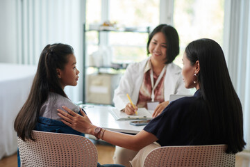 Mother and teenage girl visiting pediatrician in medical clinic