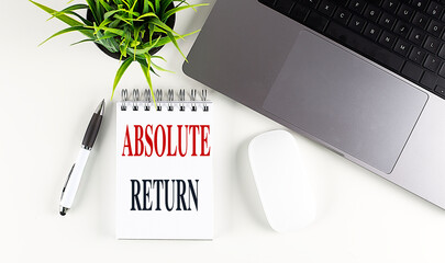 ABSOLUTE RETURN text on notebook with laptop, mouse and pen