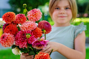 Close up of little preschool girl with dahlia flower bouquet. Close-up of happy child holding colorful garden summer flowers for mothers day or birthday. Closeup of flowers in rainbow colors.