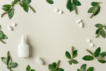 Seasonal allergy concept, spring young branches tree with new green leaves and catkins, white nasal spray, medical pills on beige background, minimal creative top view, trend flat lay photo