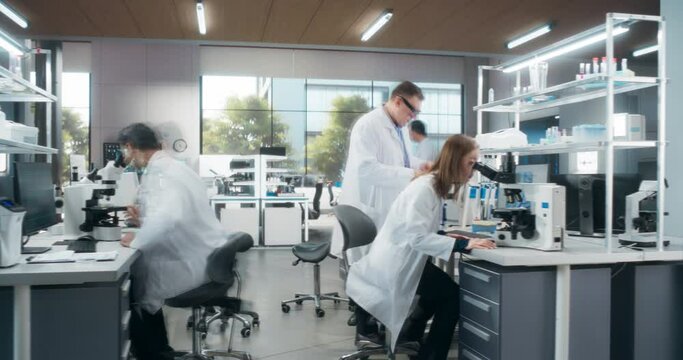 Team of Diverse Male and Female Medical Research Scientists Work on a New Generation Medical Products in a Modern Laboratory. Scientists Working on Computers and Walking in Office. Timelapse Footage