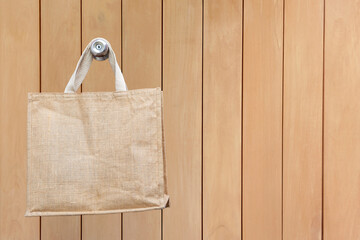 Nature eco-friendly grocery shopping bag, Jute tote bag with self handles hanging on wooden doll background