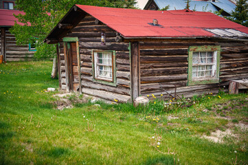 Weathered log cabin, indicative of colorado's rich history, stands in a mountainous landscape, representing the enduring spirit of the heart land's nature