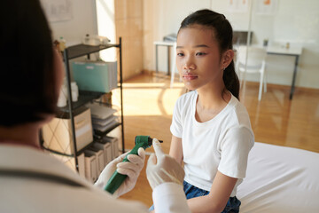 Otolaryngologist explaining teenage girl how otoscope works before examining her ears