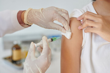 Closeup image of physician injecting vaccine in arm of girl