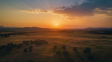 The sun is setting over a vast, empty field. The sky is filled with clouds, and the sun is just beginning to set. The scene is peaceful and serene