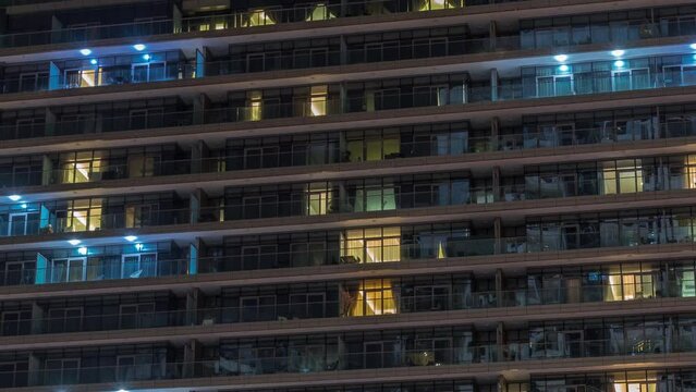 Tall blocks of flats with glowing windows located in residential district of city aerial timelapse. Evening light in rooms in towers and skyscrapers illuminated by night