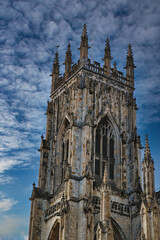 Fototapeta na wymiar Gothic cathedral tower against a dramatic cloudy sky, showcasing intricate architectural details and spires, ideal for historical or religious themes in York, North Yorkshire, England.