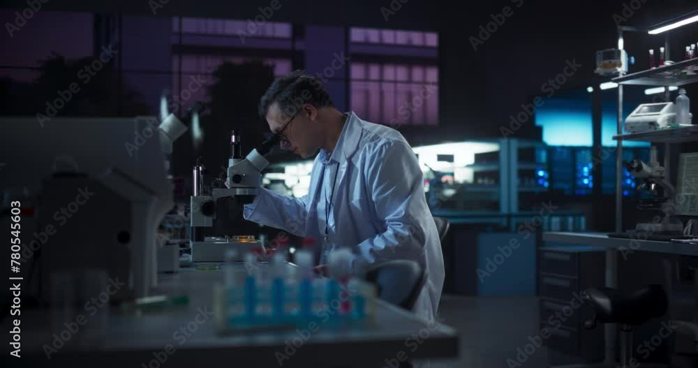 Poster portrait of a caucasian scientist working in a laboratory in the evening, using advanced microscope,