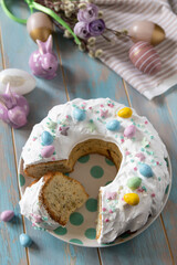 Glazed easter lemon cake decorated with confectionery and mini chocolate eggs candy on a wooden table. - 780547283