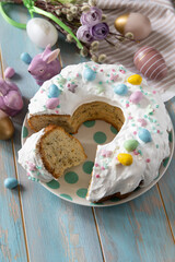 Glazed easter lemon cake decorated with confectionery and mini chocolate eggs candy on a wooden table. - 780547463