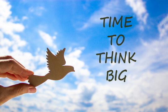 Time to think big symbol. Concept words Time to think big. Beautiful blue sky cloud background. Voter hand with wooden bird. Business and time to think big concept. Copy space.