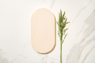 Mockup for cosmetics product presentation made with flat lay oval podium and field grass, ideal for showcasing beauty and skincare products with summer vibe.