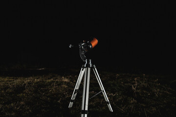 The telescope stands in a night clearing, ready and configured for observing the stars, copy space.