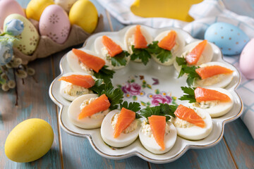 Stuffed eggs with cheese and salted salmon in the form of a carrot on a wooden table. - 780550277