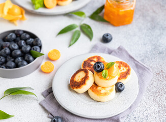 Cottage cheese pancakes, sweet curd fritters with blueberry and physalis. Syrniki with jam and berries for healthy breakfast.