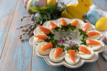 Stuffed eggs with cheese and salted salmon in the form of a carrot on a wooden table. - 780550662
