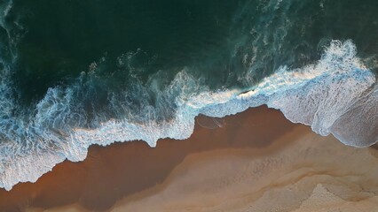 Powerful ocean wave over sand beach. Aerial top down view of sea surf on the beach