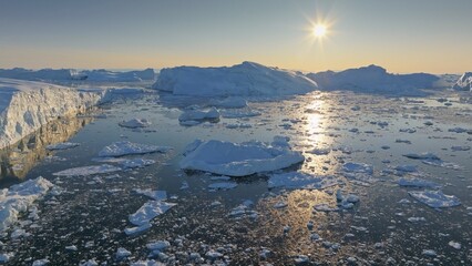 Bright sun melts pieces of the iceberg in Greenland. Aerial shot of iceberg pieces on sunny day, global warming and climate change concept - 780555028