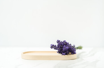 Elegant cosmetics product presentation with beige podium and lavender flower on white background. Ideal for showcasing beauty and cosmetics products. Soft focus background.
