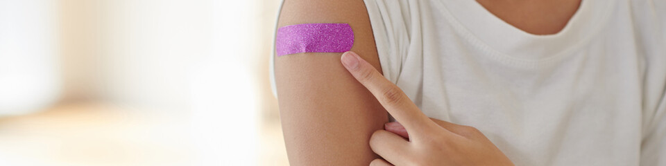 Header with teenage girl pointing at pink bandage on arm