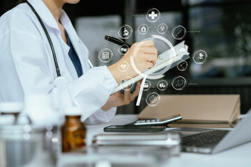 Female medicine doctor, physician or practitioner in lab room writing on blank notebook and work on laptop computer with medical stethoscope on the desk at hospital. Medic tech concept. - obrazy, fototapety, plakaty
