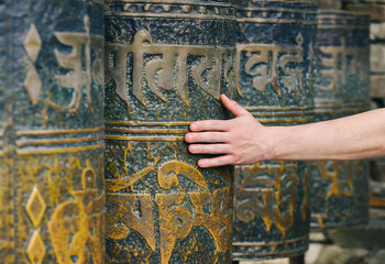 Man's hand spins Nepalese prayer wheels, close-up