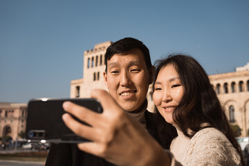 Asian man and woman travelling in Armenia taking selfie photo in Republic Square of Yerevan
