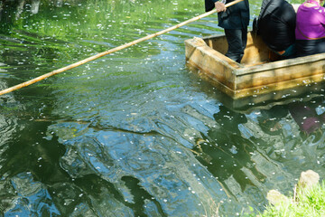 木造の小舟で客を乗せて操船する船頭の男性｜伝統的な川下りの風景