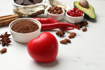 Natural aphrodisiac. Different food products and heart model on white marble table, closeup