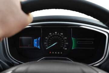 Man driving car with speedometer on dashboard, closeup
