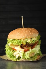 Burger with delicious patty on gray table against dark background