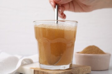 Dietary fiber. Woman stirring psyllium husk powder in water at table, closeup