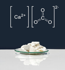 Calcium carbonate chip in chemical watch glass with molecular structure on white laboratory table....